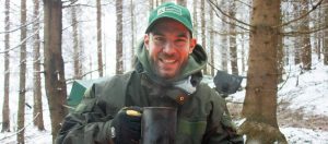 Bei unserem Survival Training Berlin lacht Maurice Ressel mit einer Kaffeetasse in der Hand in die Kamera
