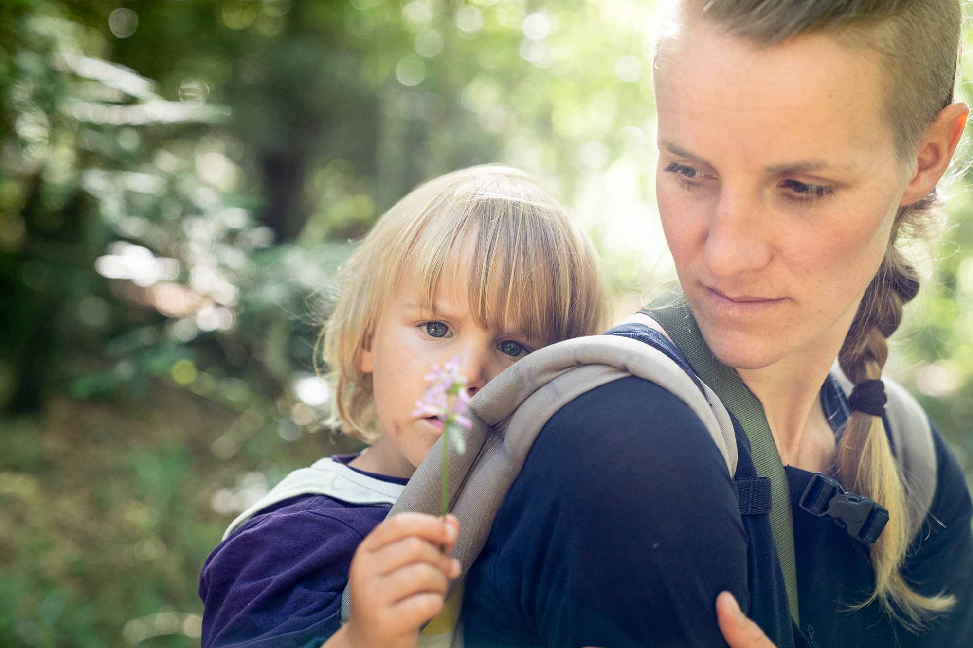 Eine Mutter zeigt ihrem Kind bei einer Wildnispädagogik Familienaktivität eine Blume