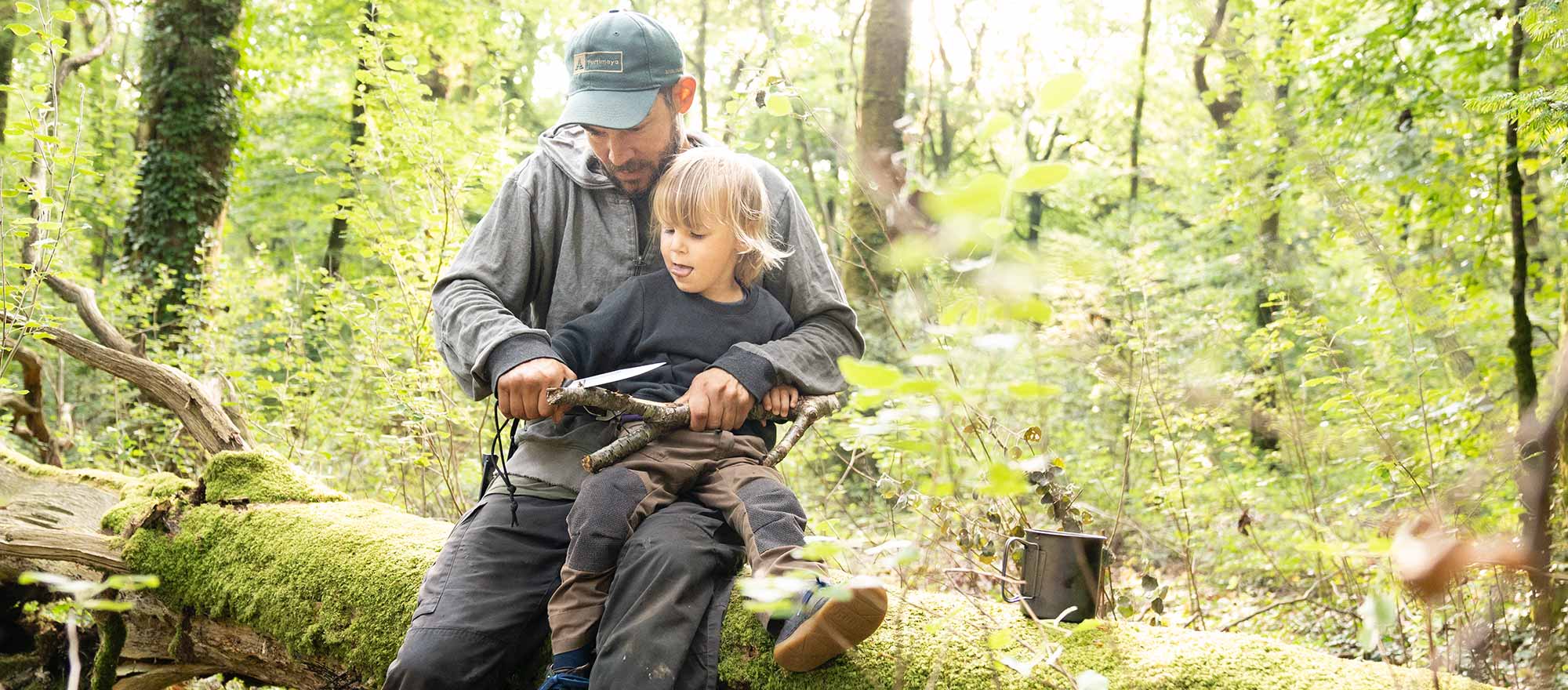 Vater und Sohn schnitzen bei einer Familienaktivität bei Berlin Vater und Sohn schnitzen bei einer Wildnispädagogik Familienaktivität bei Berlin