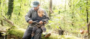 Vater und Sohn schnitzen bei einer Wildnispädagogik Familienaktivität bei Berlin