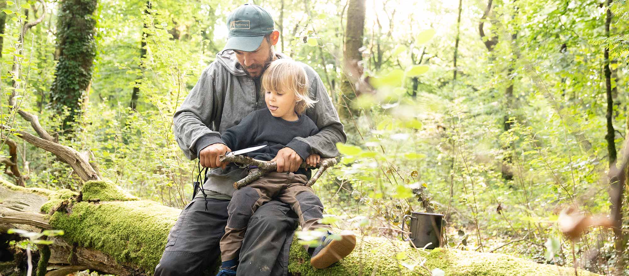 Vater und Sohn schnitzen bei einer Wildnispädagogik Familienaktivität bei Berlin