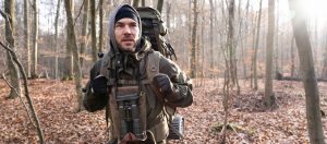 Der Bushcraft und Survival Trainer Maurice Ressel läuft mit seiner Ausrüstung durch dem Wald.