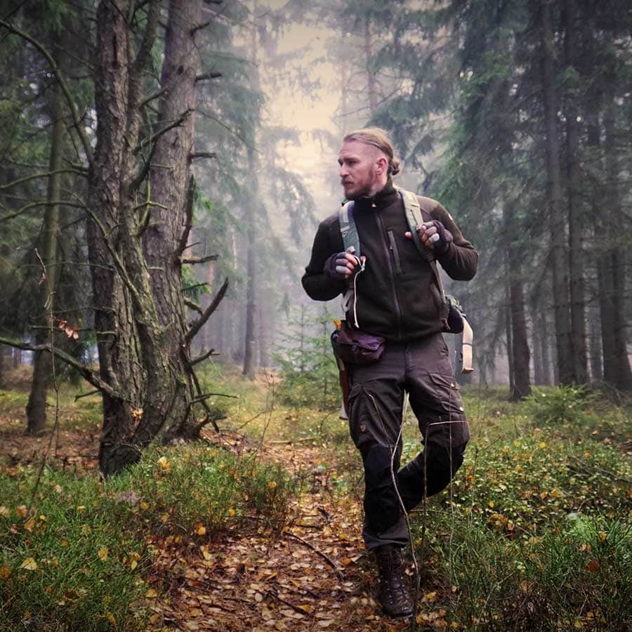 Der Survival-Psychologie Trainer und Wildnispädagoge Tobias Lehmann läuft durch einen Wald mit Nadelbäumen.