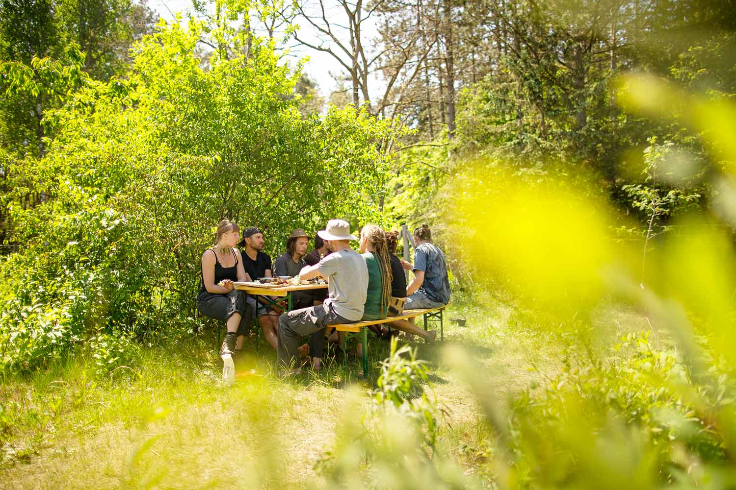 In der Mittagsonne sitzt die Gruppe der Wildnispädagogik-Ausbildung in Eberswalde am Bierbänken im Schatten und isst von unserem leckeren Essen.