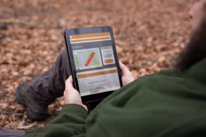 Ein Jagdschüler sitz an einem Baum angelehnt auf dem Waldboden. Er lern mit dem Online-Lernsystem der Jagdschein-Akademie im Eigenstudium, bevor der zu uns in die Jagdschule kommt.