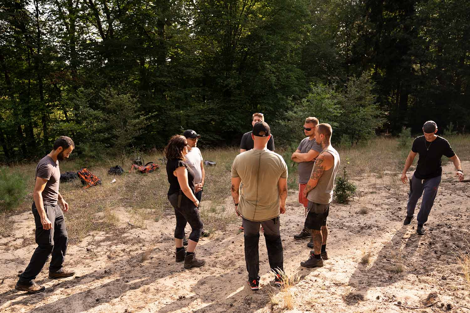Die Teilnehmer und Teilnehmerinnen der Wildnispädagogik-Ausbildung stehen beim Scout-Training im Kreis und haben die Augen geschlossen. Von außen schleichen sich.