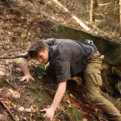 Daniel Atila erprobt im Wald sein Kampfmethode und schlängelt sich durch das Gestrüpp. Rubriken-Bild für unseren Survival-Selbstverteidigungskurs