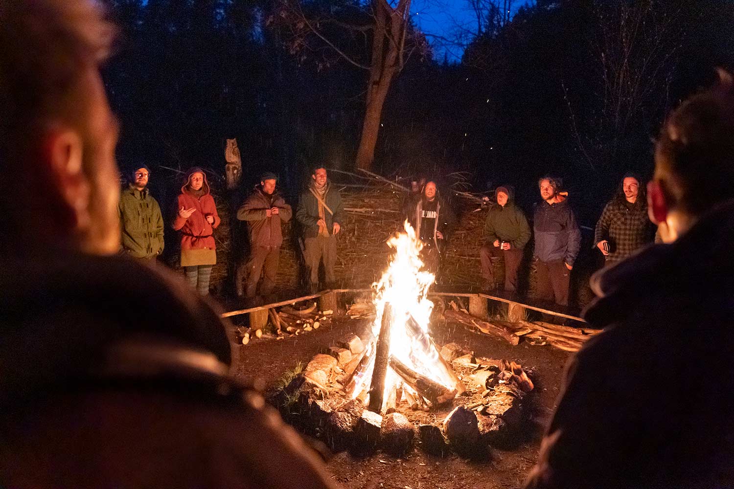 Die Teilnehmer unserer Wildnispädagogik-Ausbildung stehen dicht am Lagerfeuer und singen.