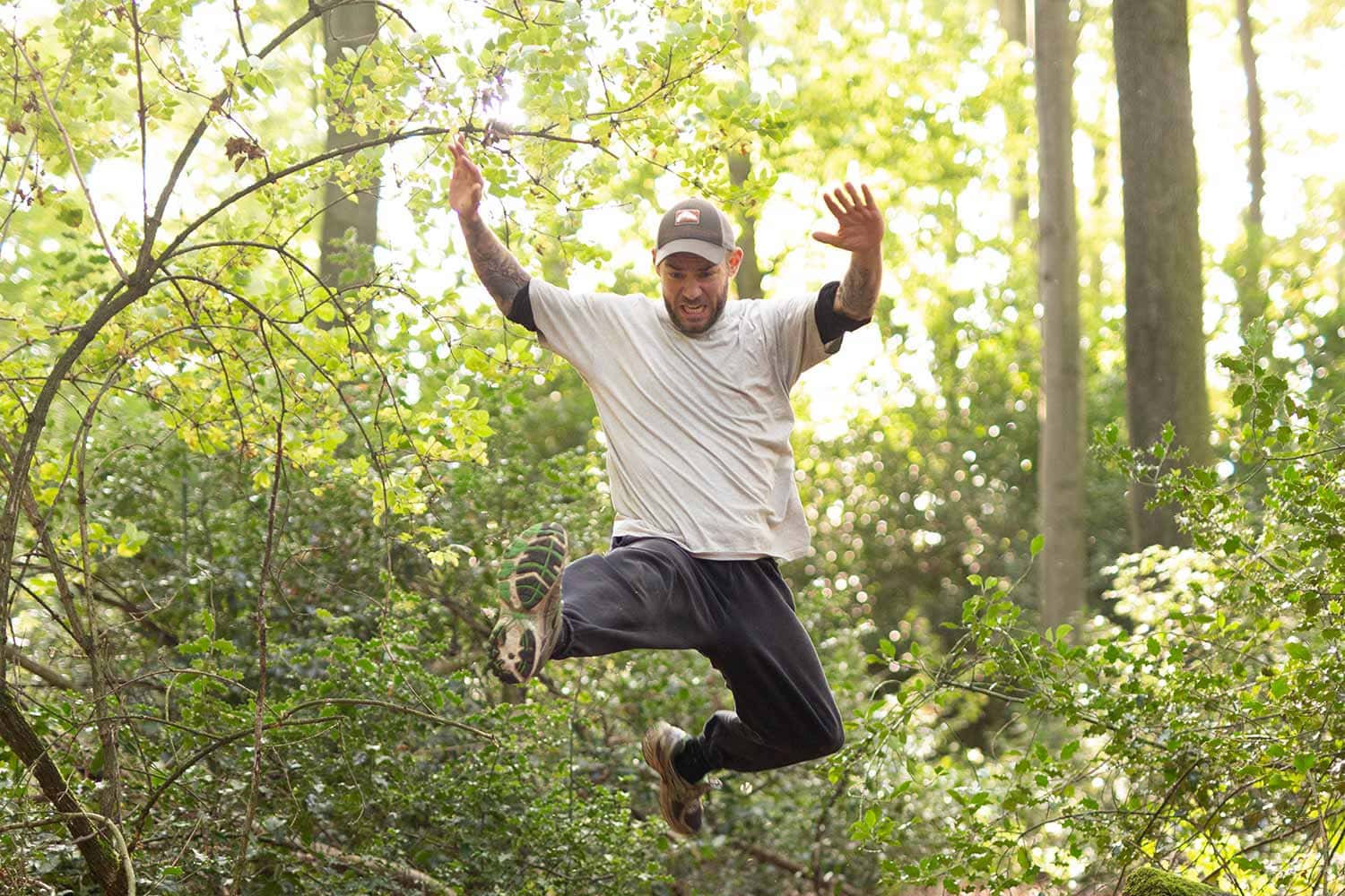 Maurice Ressel spring bei seinem Outdoor Bodyweight Training über einen Baumstamm.