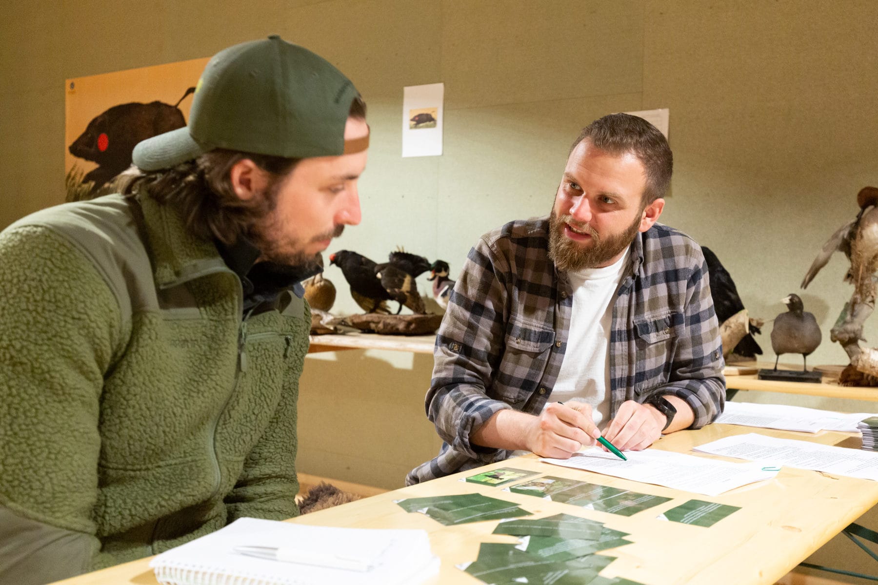 Dozent in Jagdausbildung sitzt mit Jagdschüler am Tisch um die Prüfung vorzubereiten