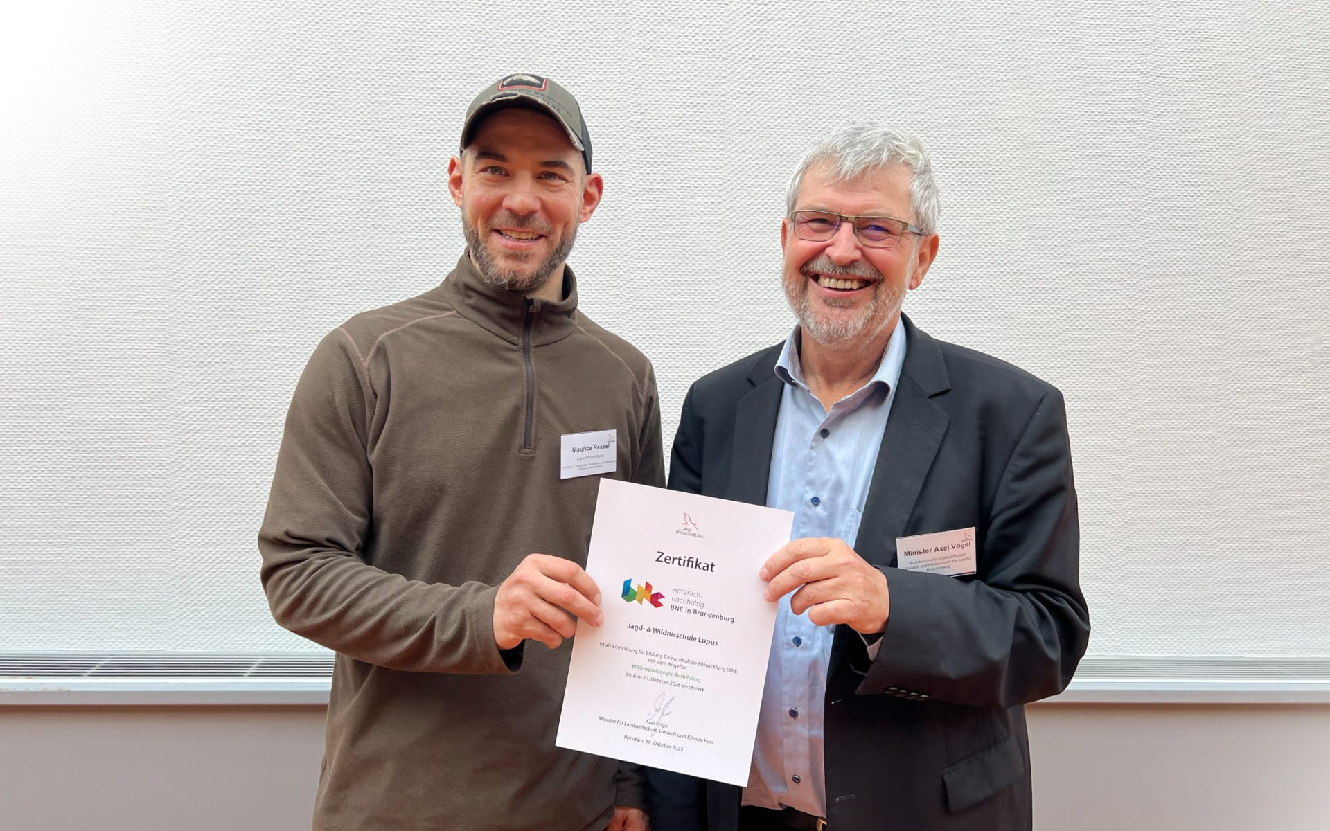 Axel Vogel übergibt Maurice Ressel, dem Gründer der Wildnisschule, das Zertifikat für Bildung für nachhaltige Entwicklung