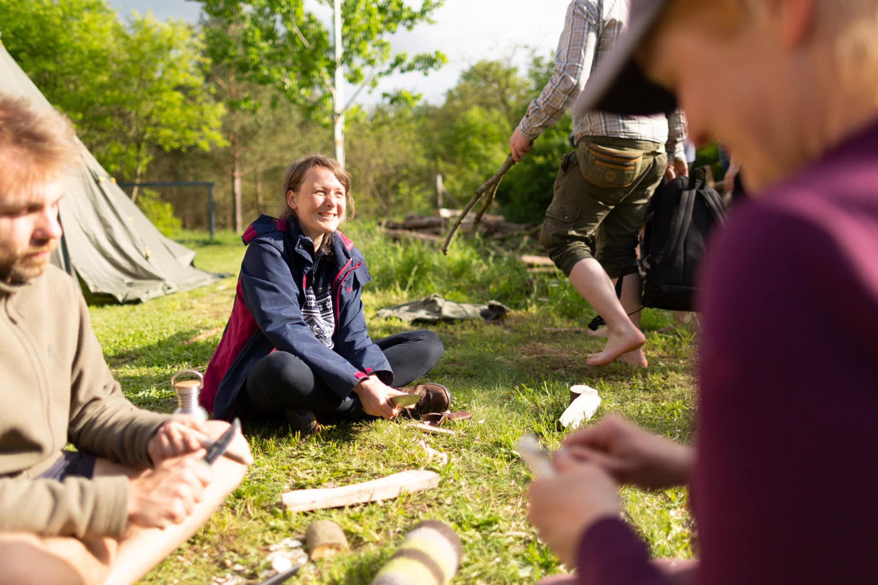 Eine kleine Gruppe von Teilnehmern unserer Wildnispaedagogik-Ausbildung sitzen zusammen auf einer Wiese unserer Wildnisschule