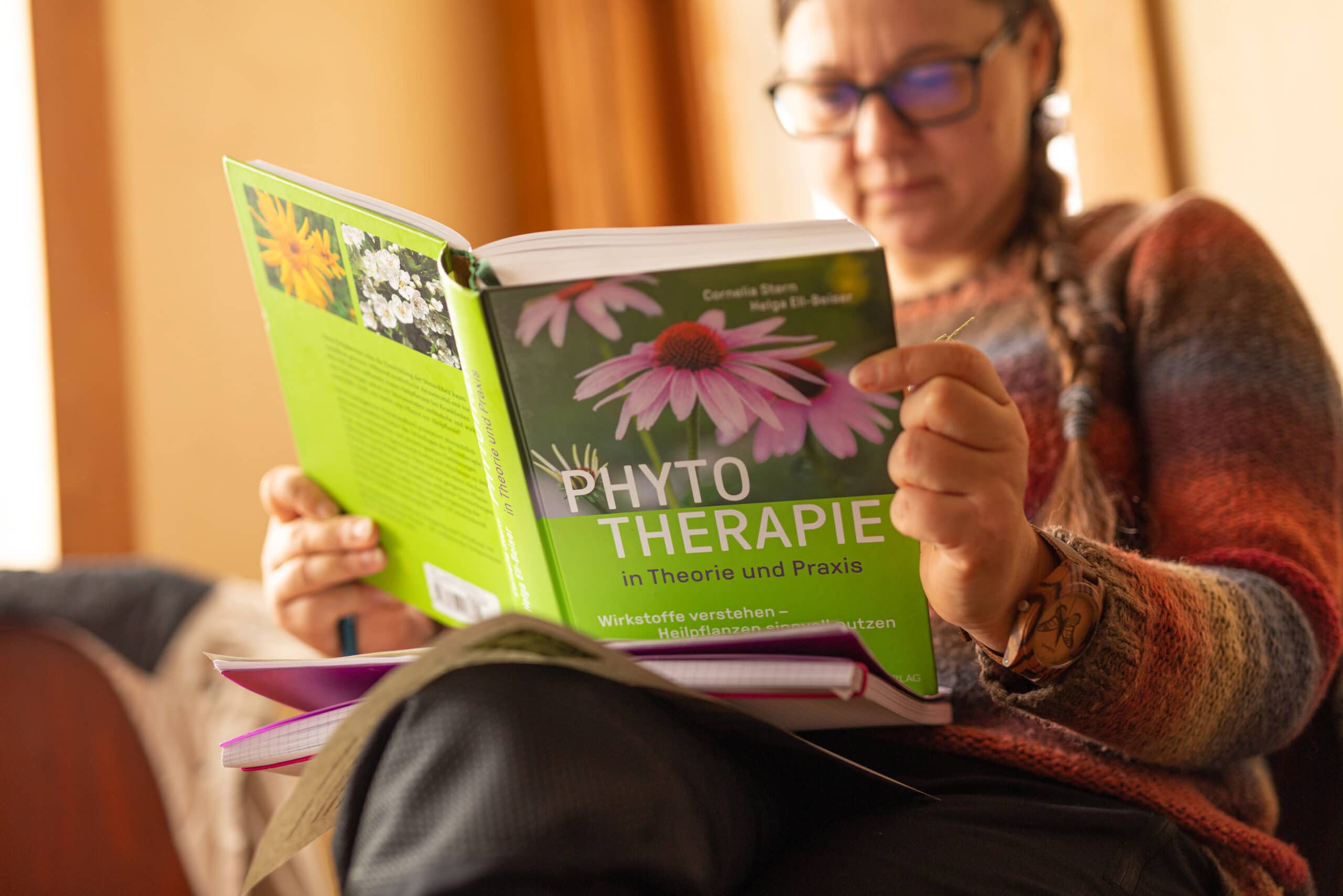 Eine Teilnehmerin sitzt im Seminarraum und liest ein Sachbuch über Phytotherapie.