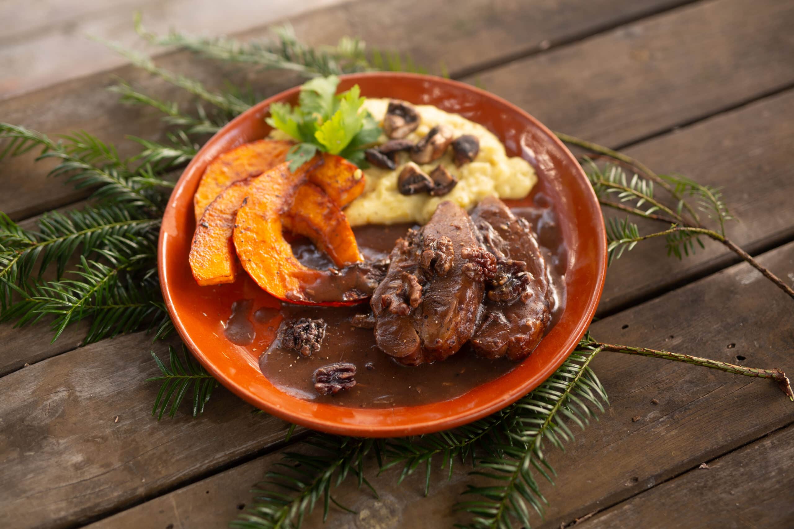 Auf einem Holztisch der Jagdschule ist für die Schüler ein jeganes Gericht mit Wildfleisch, Kartoffelbrei und Kürbis angerichtet.