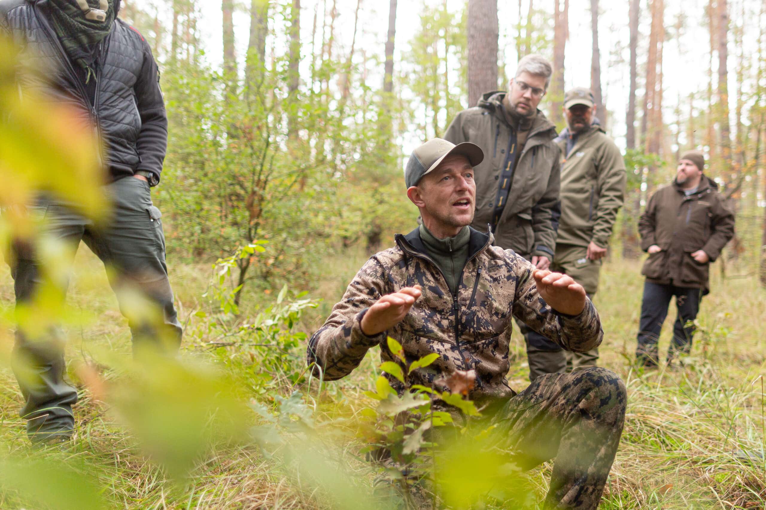 Im Fach Jagdpraxis sitzt der Dozent und Jagd-Experte Kai Hagemann auf dem Waldboden und erzählt den Schüler alles über Verbissschäden an einer jungen Eiche.