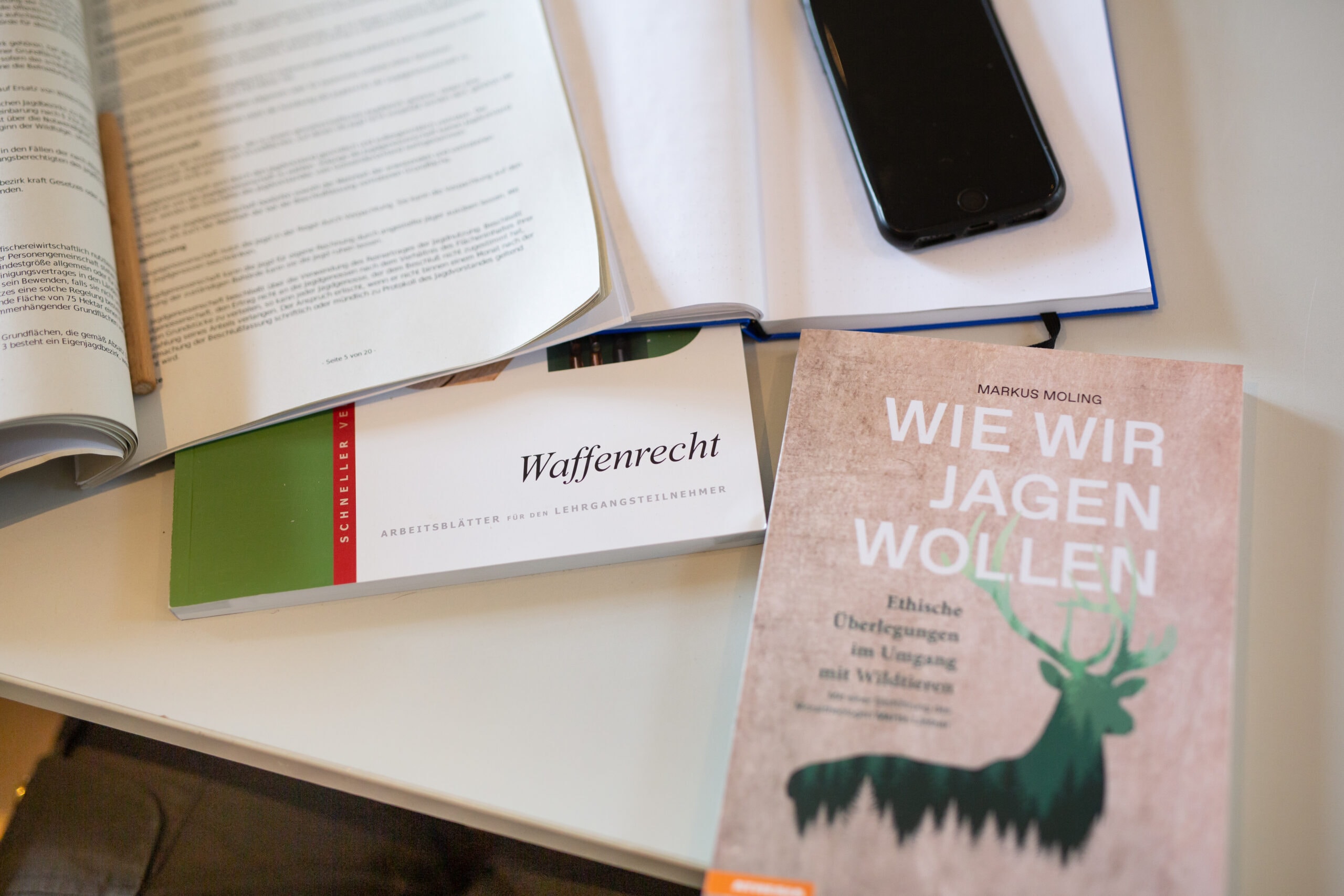 Verschiedene Lernmaterialien wie der Heintges und das Buch wie wir jagen wollen von Markus Moling liegen auf dem Tisch der Jagdschule.