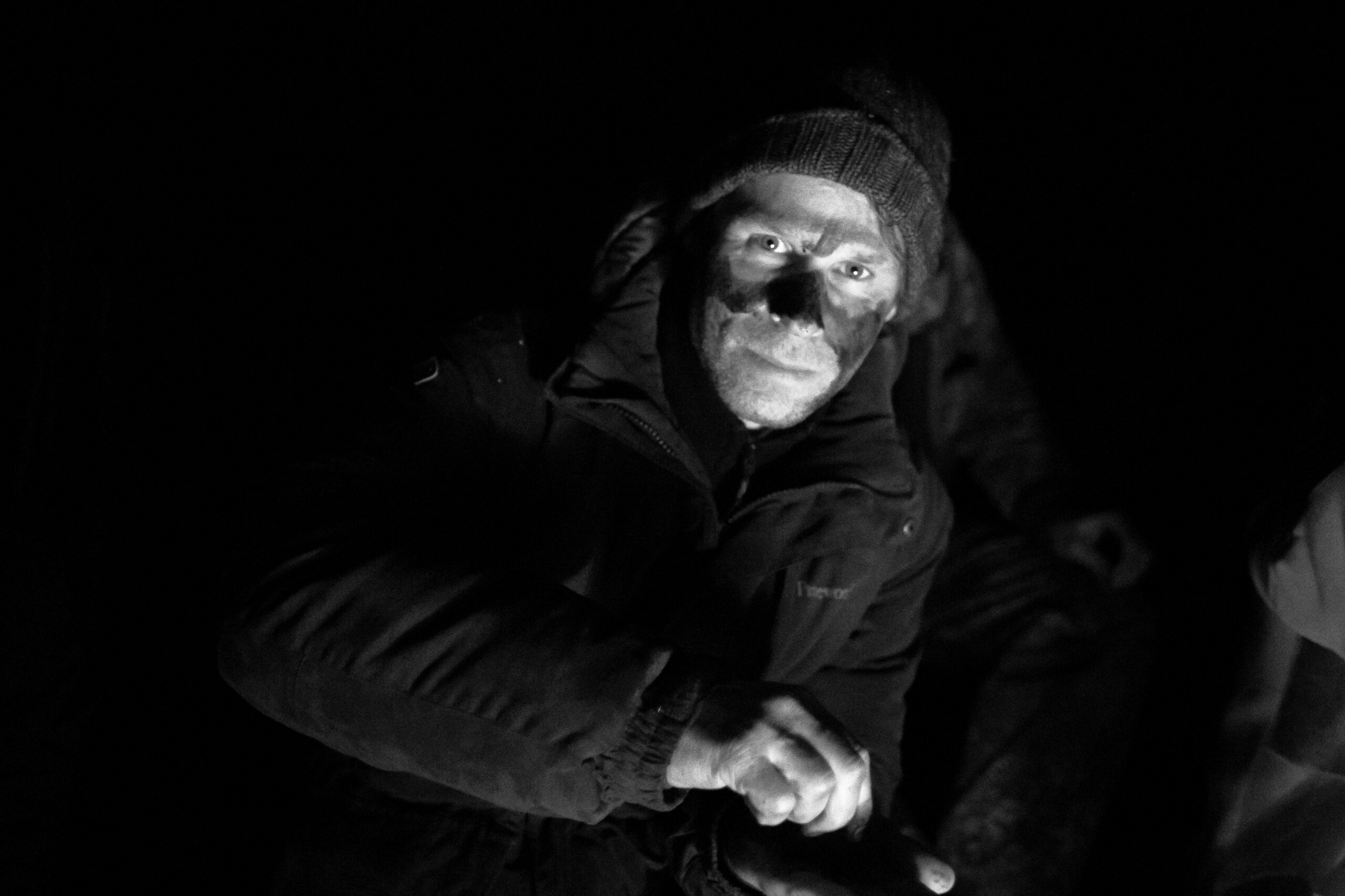 Der Co-Teamer des Scout-Training Marcel Klemm sitzt am Lagerfeuer und tarnt sein Gesicht vor einer Scout-Mission mit Kohle.