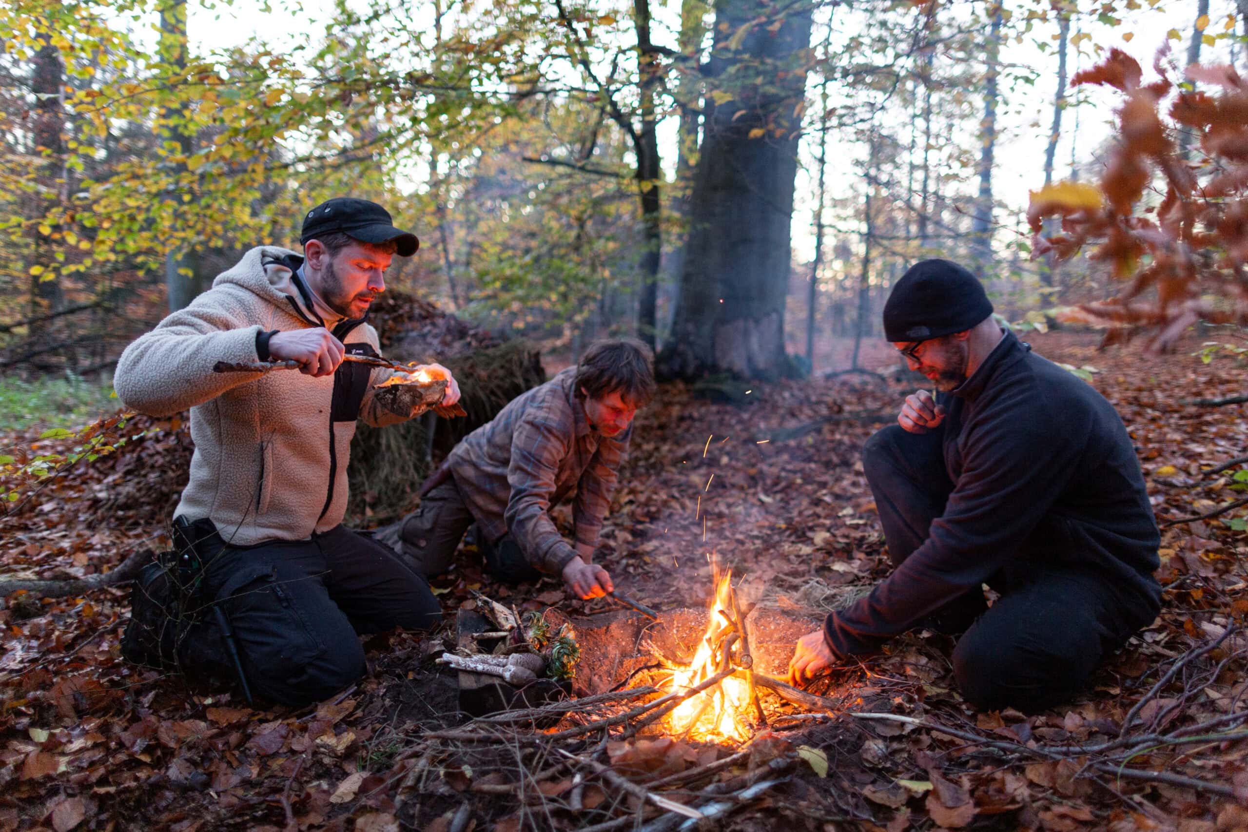 Maurice Ressel und Teilnehmer am Lagerfeuer im Herbstwald — Gemeinschaft während der Survival-Ausbildung