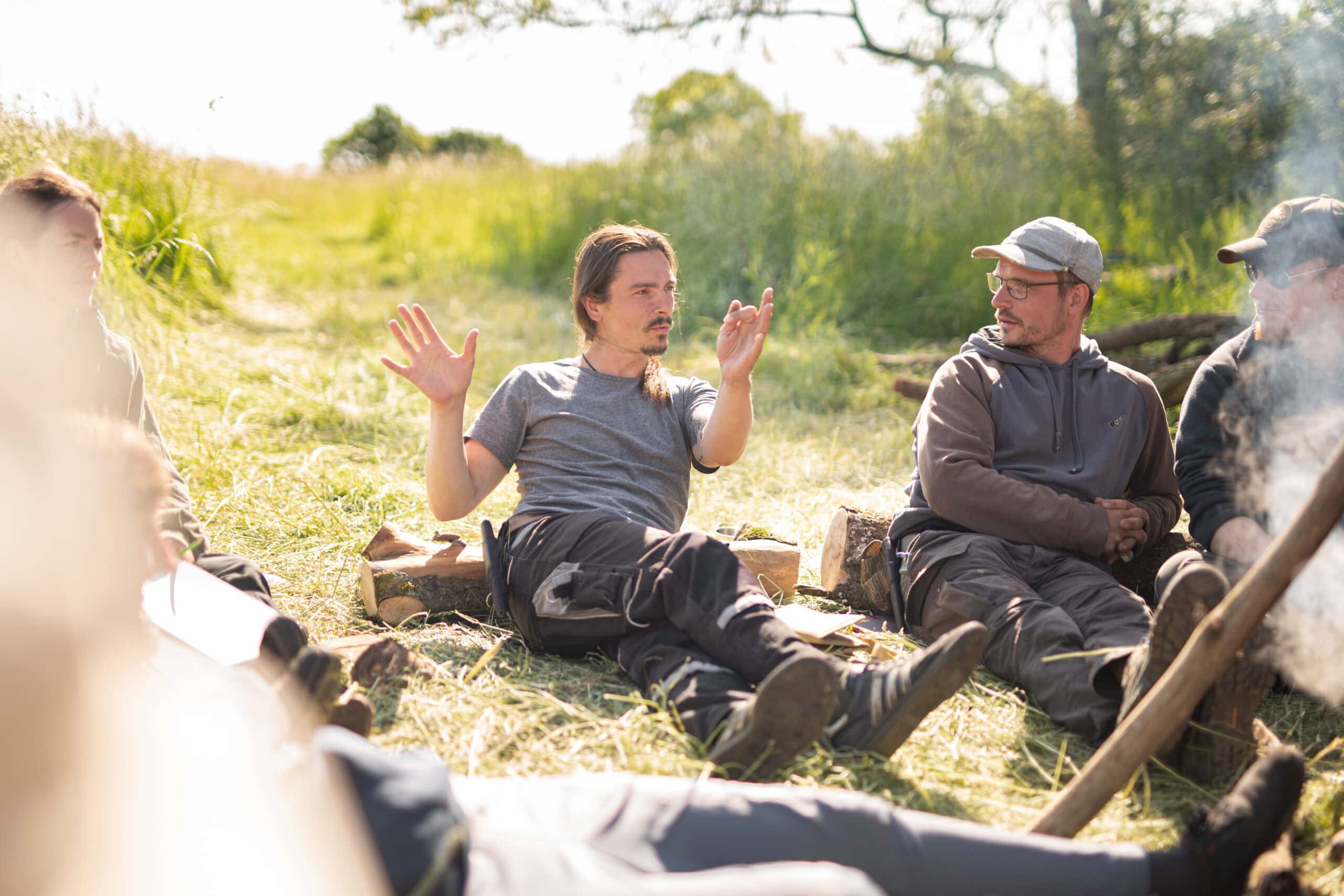 Teilnehmer der Survival-Ausbildung im Gespräch am Lagerfeuer — authentischer Erfahrungsaustausch nach dem Training
