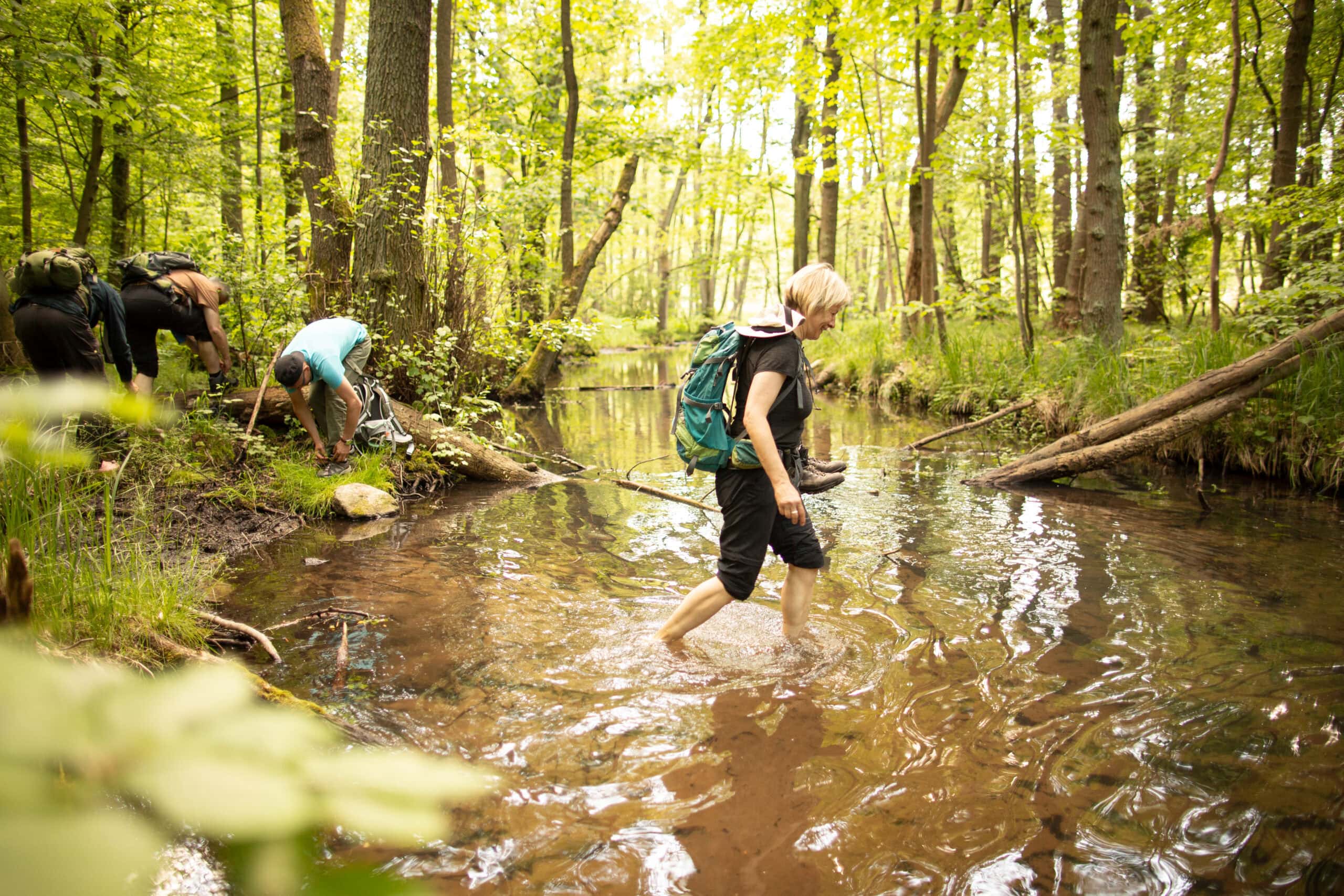 Teilnehmer bei Bachquerung während des Survival Trainings — Geländeübung barfuß im Wald bei Maurice Ressel