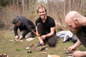 Teilnehmer beim Feuermachen im Survival Training — brennendes Zunderbündel aus Birkenrinde bei Maurice Ressel